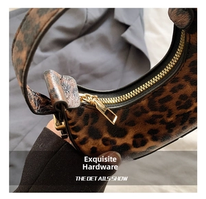 Detailed macro view of high-quality golden metal zipper on leopard print crescent bag