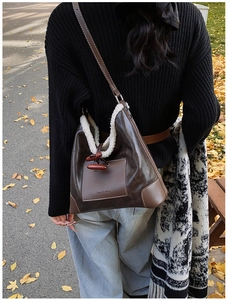 Detail of dark brown leather tote bag with white faux fur lining and wooden toggle button
