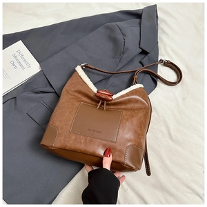 Detail of a brown leather bucket bag with white faux fur trim and wooden toggle closure