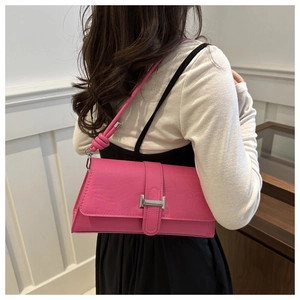 Detail of fuchsia stone-embossed faux leather baguette bag with silver hardware and knot strap