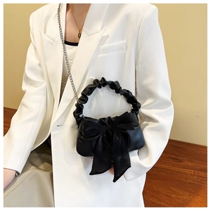 Detail of black bow handbag featuring ruched handle and silver metal chain strap