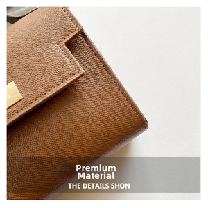Macro view of brown lychee grain leather texture with gold hardware and fine stitching