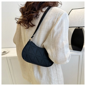 Detail of black quilted moon bag with triangular stitching on model's shoulder