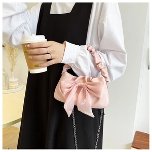 Detail of pink vintage bow handbag with ruffled handle and silver chain strap