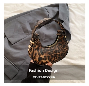 Detail of leopard print crescent hobo bag featuring gold metal buckles and zip closure