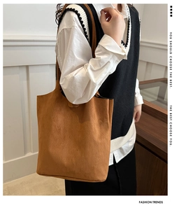 Brown suede tote bag shown on model highlighting the soft matte texture and large capacity