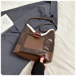 Close-up of brown leather bucket bag with white faux fur trim and wooden toggle detail