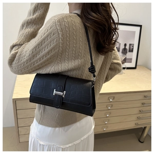 Close-up of black crocodile embossed leather shoulder bag with silver H-shaped metal buckle