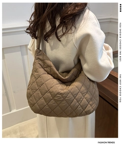 Detail of a brown quilted puffer shoulder bag with diamond stitching and wide strap