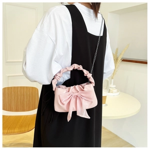 Pink bow handbag with pleated handle and silver chain strap shown worn by a model