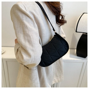 Detailed view of a black quilted shoulder bag with slim straps worn by a model