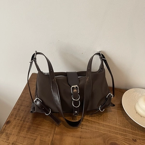 French-style dark brown shoulder bag with silver buckles on a wooden table