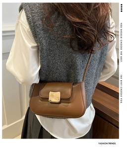 Model wearing a vintage brown leather shoulder bag with a gold square clasp on the back