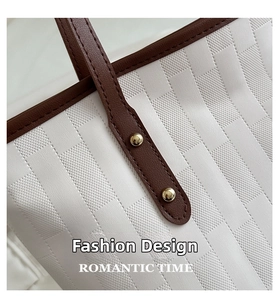 Detail of white geometric textured tote bag with brown leather strap and gold metal rivets