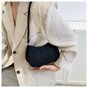 Close-up of black quilted hobo bag with geometric triangular texture on shoulder