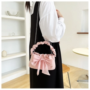 Close-up of pink handbag featuring a large organza bow and ruffled cloud handle detail