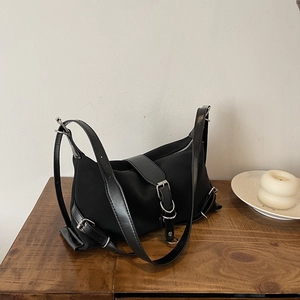Minimalist black shoulder bag in French style with silver hardware on a wooden table