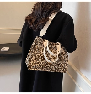 Detail of leopard print canvas tote bag featuring adjustable strap on black coat