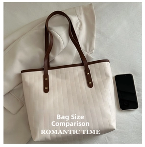 Close-up of cream woven tote bag with brown leather handles and smartphone for size scale