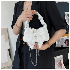 Elegant white bow handbag with ruched handle and chain strap on stylish model