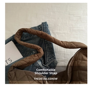 Detailed view of the wide padded shoulder strap on a brown quilted nylon crossbody bag