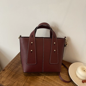 Deep red lychee pattern bucket bag with white contrast stitching and gold rivets