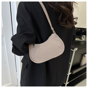 Rear view of a model wearing a beige felt half-moon shoulder bag with quilted texture