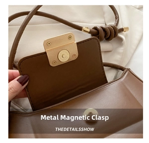 Detail of the high-quality golden magnetic closure on a brown leather baguette bag