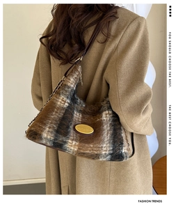 Dettaglio della borsa hobo in lana a scacchi con logo in metallo e tracolla su modella