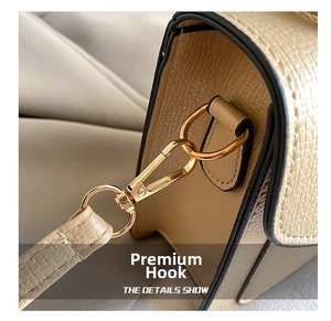 Detailed macro view of the golden metal hook and litchi grain leather on a beige handbag