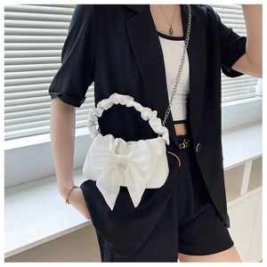 Detail of white pleated cloud bag featuring large mesh bow and chain shoulder strap