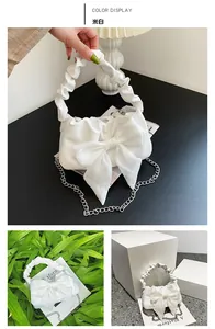 Detail of off-white handbag featuring a large silk bow and pleated cloud-style handle
