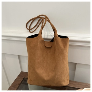 Detail of a brown suede tote bag featuring slim shoulder straps and high-quality texture