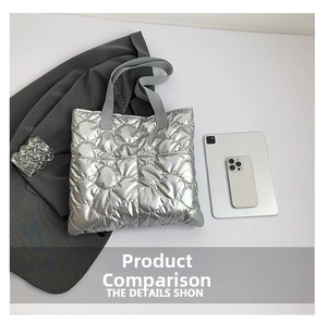 Gros plan d'un sac cabas argenté matelassé avec des poignées grises sur un bureau blanc chic