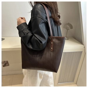 Macro shot of dark brown tote bag with rectangular brick texture and gold rivet detail