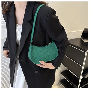 Close-up of green felt fabric shoulder bag with triangular quilting and gold hardware
