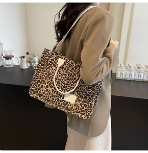 Detailed view of leopard print tote bag with white woven handles in a cafe setting