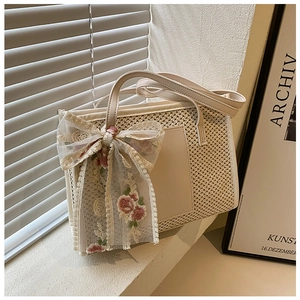 Detail of cream woven tote bag featuring a large lace flower ribbon and leather handles