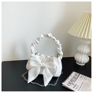 Detail of white bow handbag with cloud handle and elegant metal chain strap