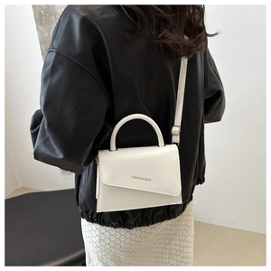 Petit sac blanc minimaliste porté par un mannequin avec veste en cuir et jupe blanche