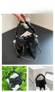 Detail view of black vintage handbag with large bow and ruffled handle and chain