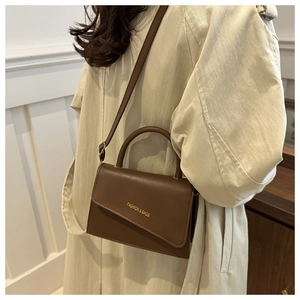 Détails du sac à main en cuir marron foncé avec rabat asymétrique et lettrage doré