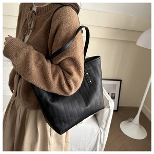 Detail of black faux leather tote bag with brick embossed texture and gold rivets