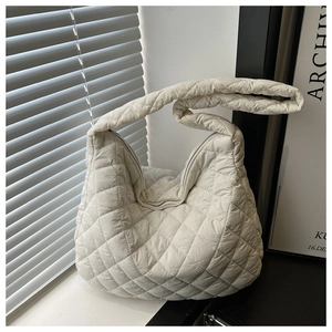 Macro detail of creamy white quilted hobo bag featuring soft diamond stitching texture