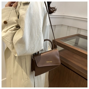 Gros plan d'un petit sac bandoulière vintage marron foncé avec poignée incurvée