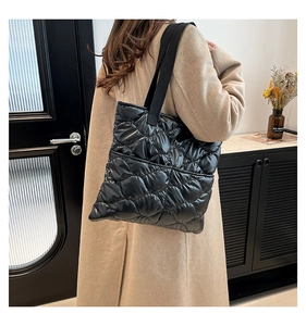 Vue latérale du sac cabas matelassé noir en nylon brillant porté par un mannequin