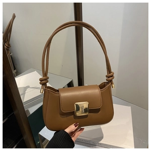 Detail of caramel leather underarm bag with gold square buckle and knotted strap