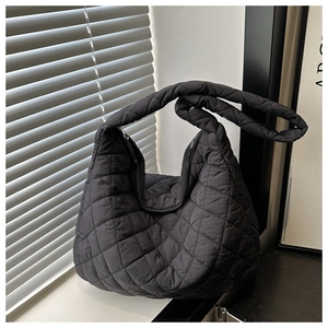 Detail of black quilted shoulder bag featuring large diamond pattern and padded texture