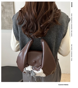 Brown leather vintage tote bag with white plush dog pendant shown on a model