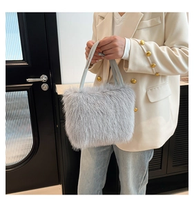 Light gray faux fur tote bag with long plush texture and slim leather handles on a model